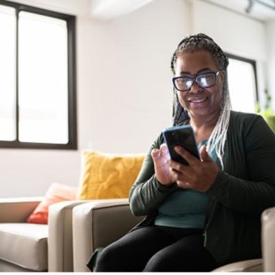 A happy person using their smart phone in their living room.